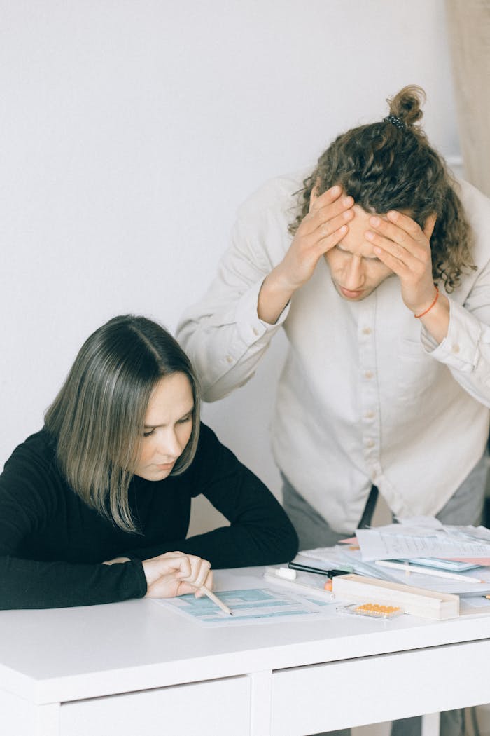 TUTVUSTUS Young couple in discussion over financial papers, looking stressed at a table indoors.